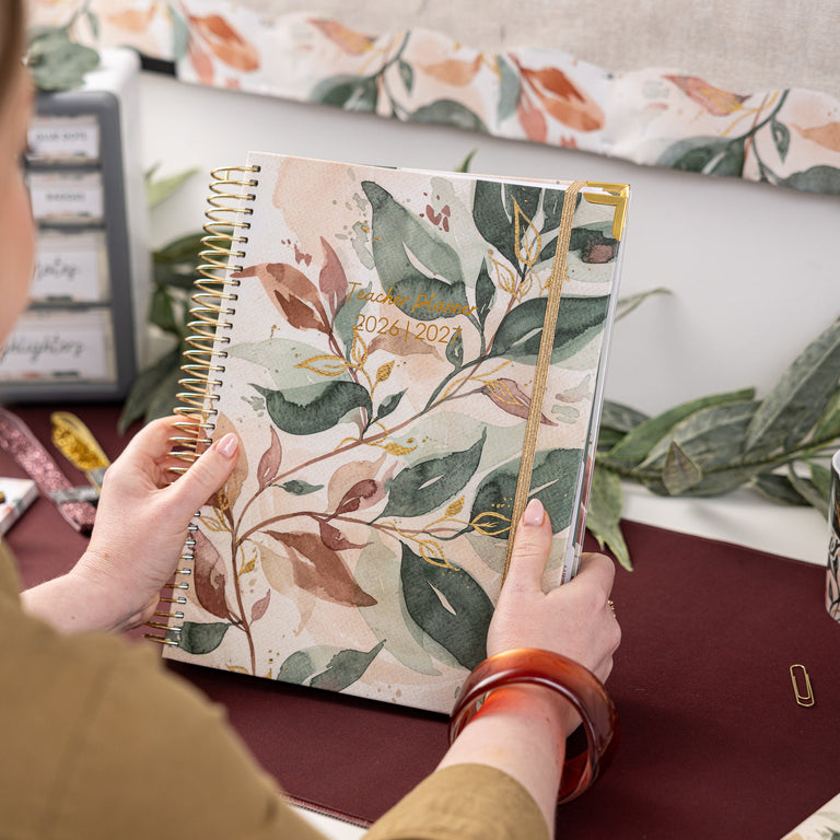 Person holding a floral notebook with a decorated wall in the background